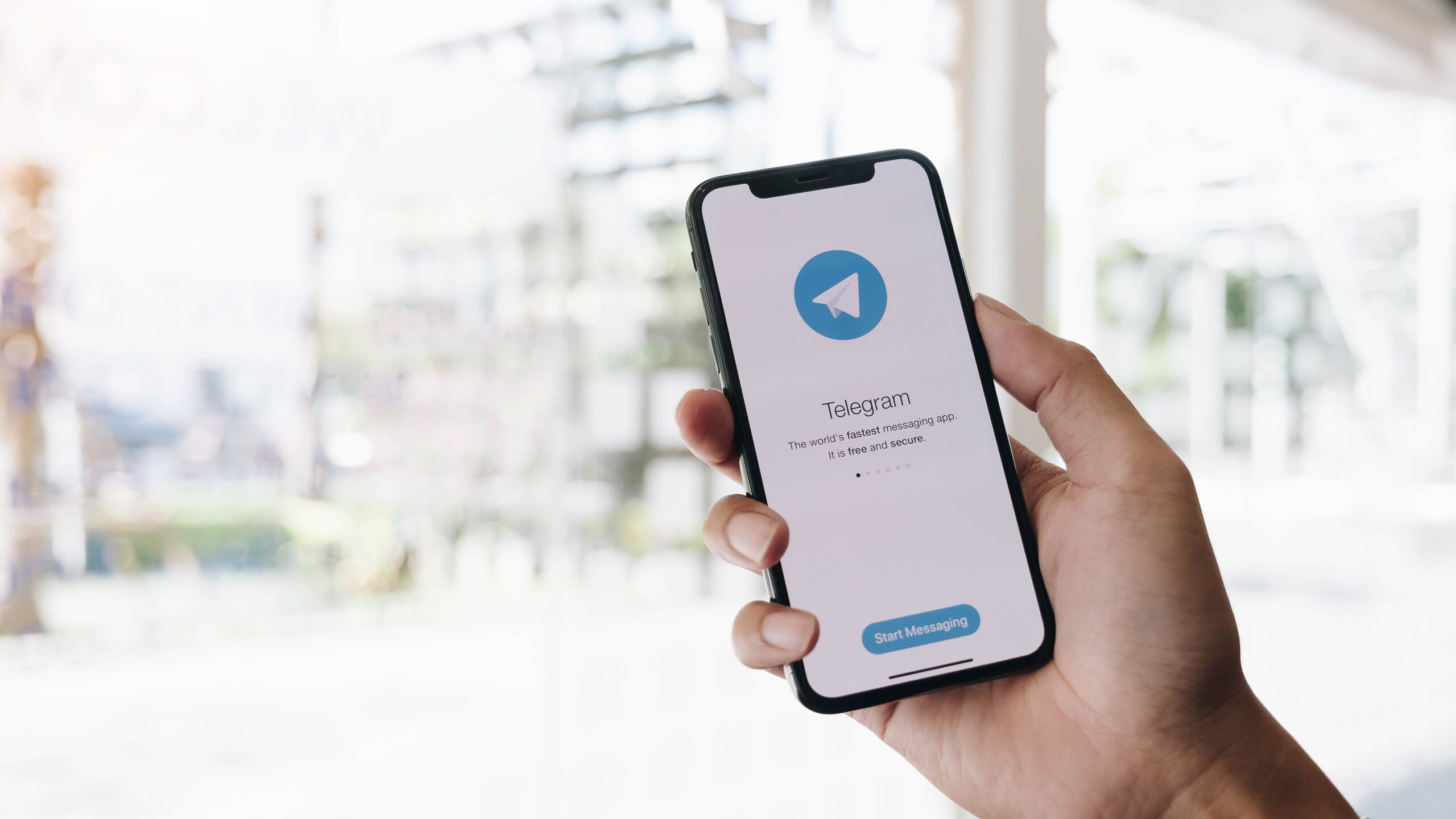 woman hand holding smartphone with telegram app on the screen scaled