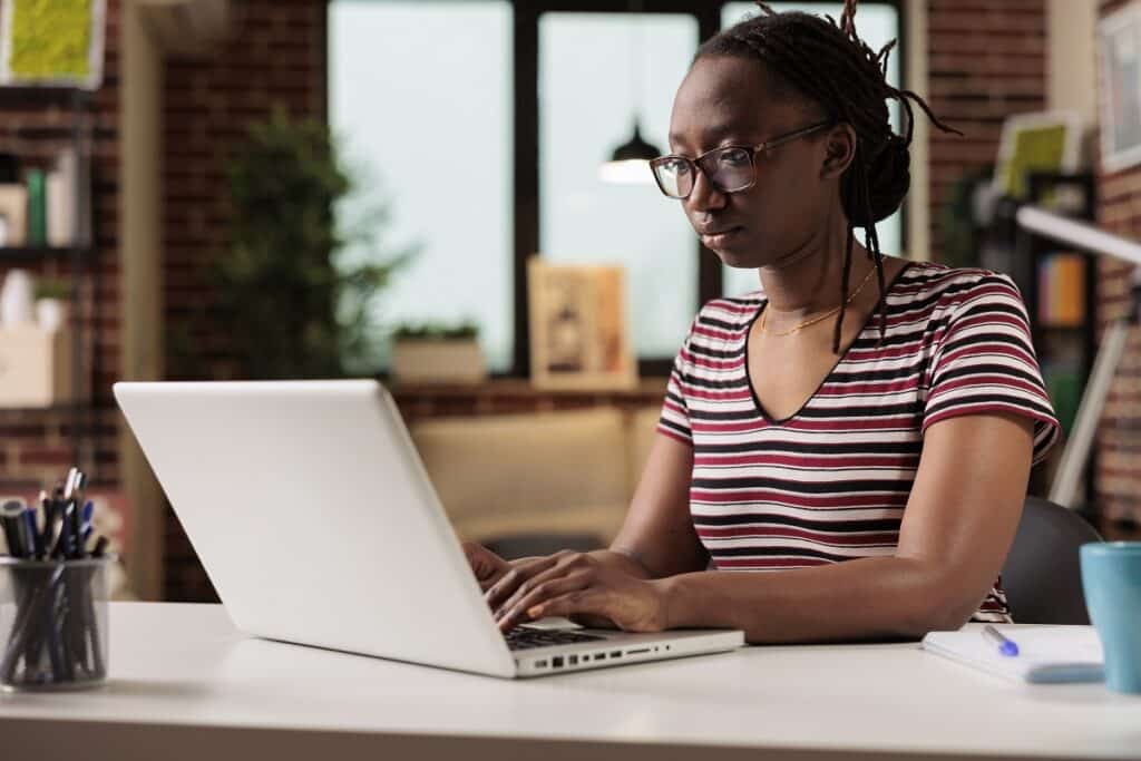 mulher negra sentada, trabalhando no seu laptop