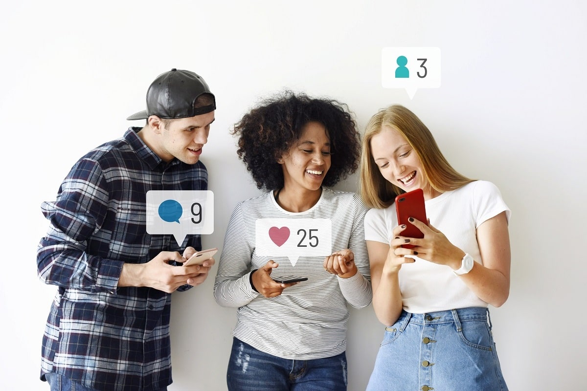 Imagem de 3 pessoas mexendo no celular em suas Redes Sociais