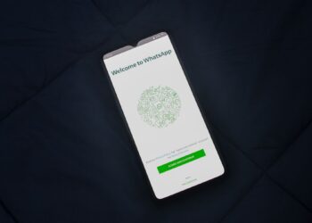 Smartphone exibindo a tela de boas-vindas do WhatsApp sobre tecido azul-marinho escuro