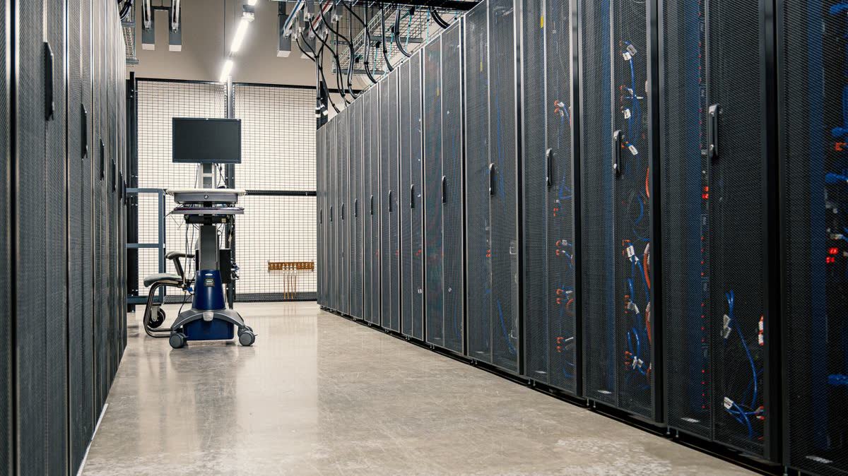 Corredor de datacenter com racks de servidores e monitor, ilustrando a infraestrutura física por trás do treinamento de modelos avançados de IA na China. Imagem: Pexels