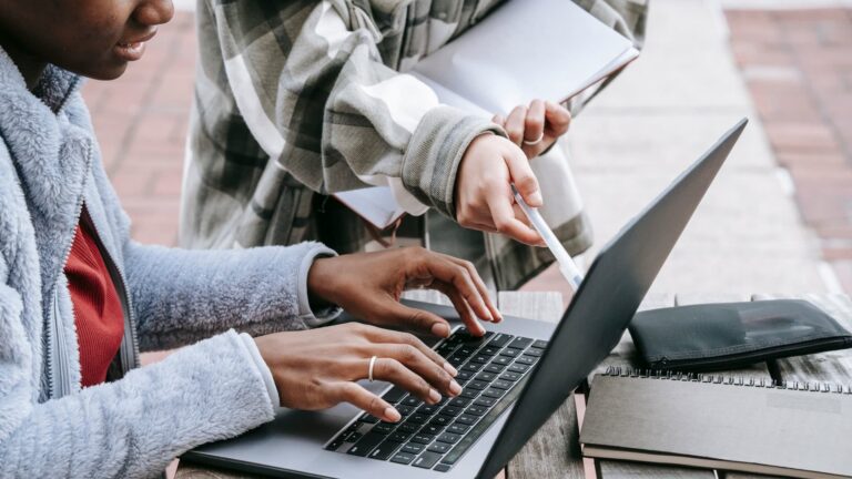 Estudantes usando notebook e anotações para estudar