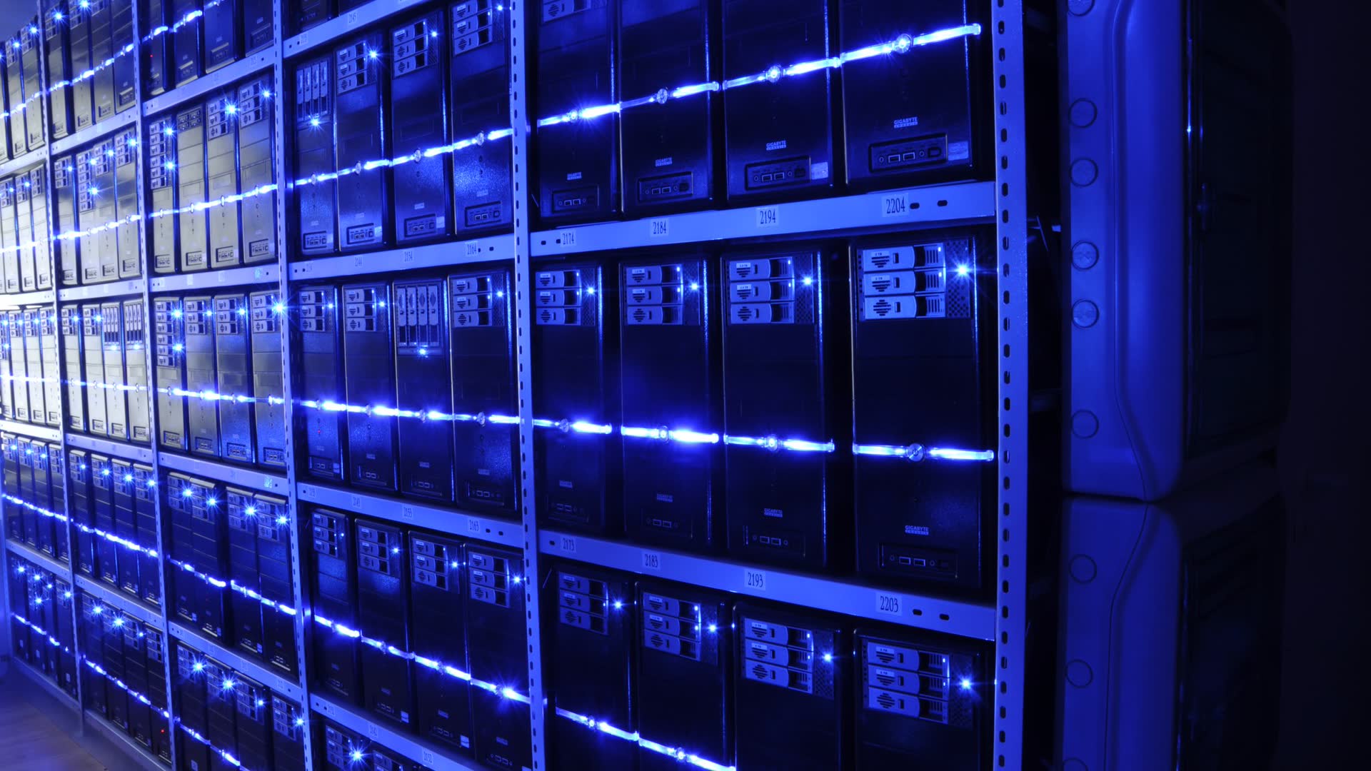 Fileiras de racks de servidores iluminados em azul em um data center.